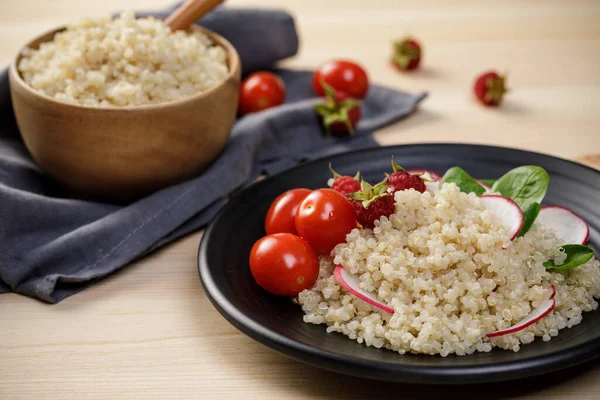 Quinoa salad with vegetables, raspberry and tomatoes on the wooden table. Super food for healthy and concept of balanced diet