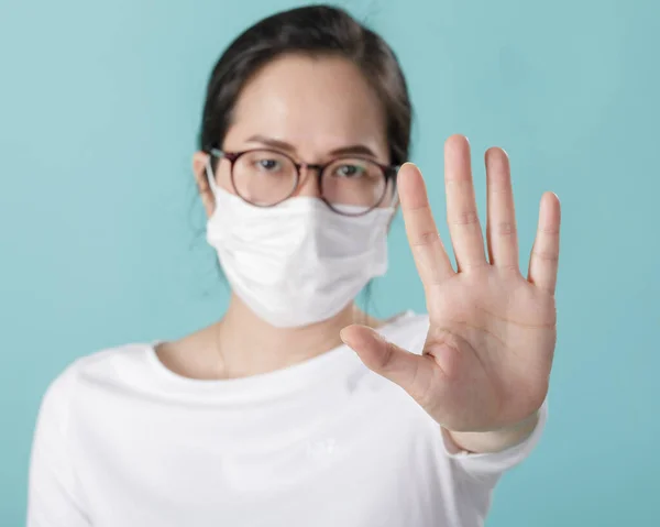 コロナウイルス発生を保護し アルコールゲルで手を洗うためにマスクマスクを身に着けているアジアの若い女性 武漢中国の概念から新しいウイルスCovid 青の背景に隔離 ストック画像