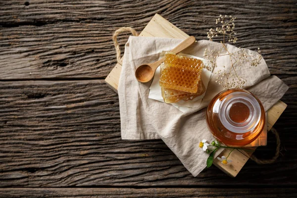 木のテーブルの上に蜂蜜のディッパーと花を持つ瓶とハニカムで蜂蜜蜂 有機天然成分の概念による蜂の製品 あなたのテキストのためのコピースペース ロイヤリティフリーのストック画像