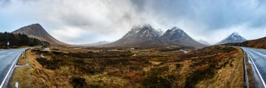 Glencoe, İskoçya 'da küçük evi olan bulutlardaki panoramik manzara
