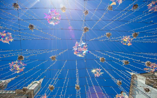 Crystal colorful butterflies with rays of light on a blue sky background