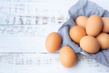 Üst manzara tavuk yumurtaları sepetin içinde beyaz ahşap masada..