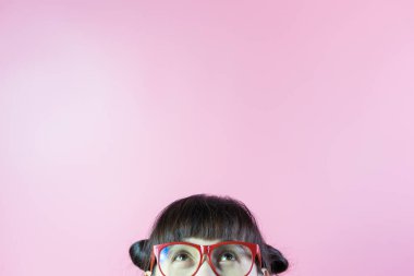 Gözlüklü komik kadının yarısı pembe arka planda boşluğa bakıyor..