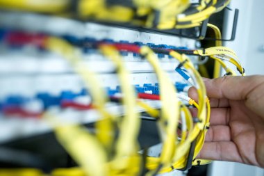 İnsan eli cam fiber kabloyu kontrol paneline yerleştiriyor.