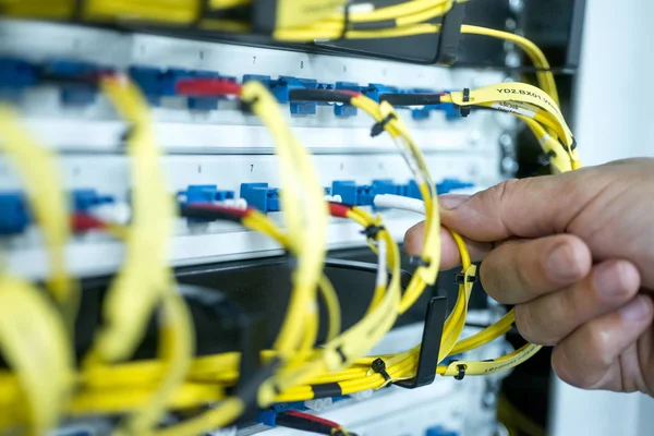 İnsan eli cam fiber kabloyu kontrol paneline yerleştiriyor.