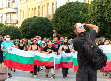 Filibe, Bulgaristan Temmuz - 10.2020: Koruyucu maskeli bir grup insan Bulgar bayraklarıyla cadde boyunca yürüyor. Yolsuzluğa ve yetkinin kötüye kullanılmasına karşı protesto. Seçici odak