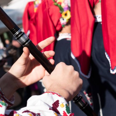 Genç müzisyenlerin elleri ahşap flütle çalar. Bulgar milli kostümlü bir adam uzun boruyla oynuyor. Kaval Balkan halk müziği geleneksel ahşap rüzgar enstrümanı.