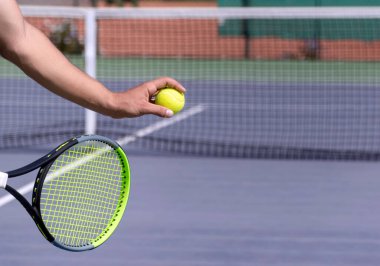 Mor sert tenis kortunda raketi ve topu olan tenisçi servis yapmaya hazırlanıyor. Maçın başlangıcı, maç, turnuva. Fotokopi alanı olan spor arka planı. Seçici odak