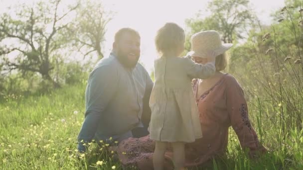 Szczęśliwa rodzina bawiąca się na trawie w ogrodzie, tata w ciąży mama i ich córka odpoczywają. — Wideo stockowe