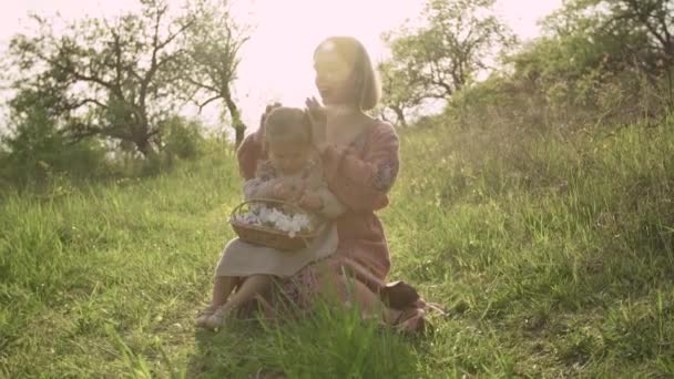 Una madre embarazada trenza el pelo de sus hijas de 2 años, en el jardín — Vídeo de stock