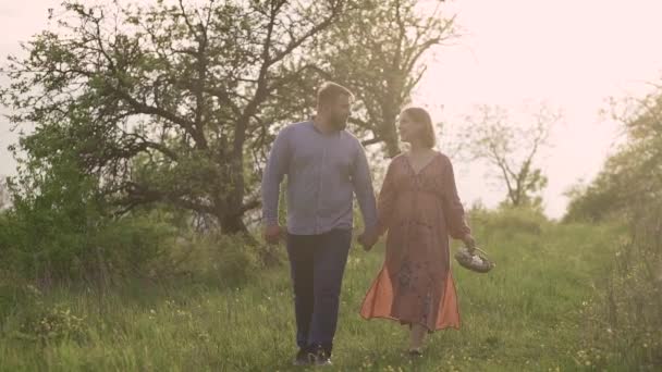 Mann und schwangere Frau spazieren im Garten, — Stockvideo