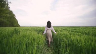 Beyaz gömlekli, etekli, beyaz saçlı beyaz bir kız buğday tarlasında yürüyor.