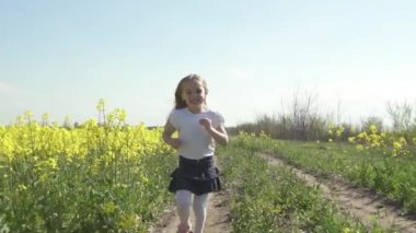 Sarı saçlı küçük mutlu kız, sarı bir tarlada koşuyor ve gülümsüyor.