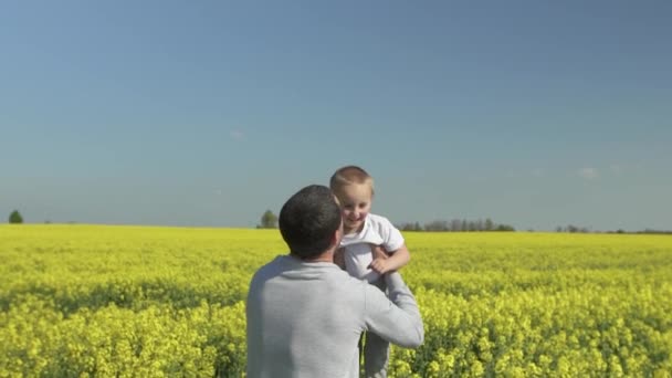 Feliz familia, papá lanza hijo hijo en un paseo en el campo floreciente de primavera . — Vídeos de Stock