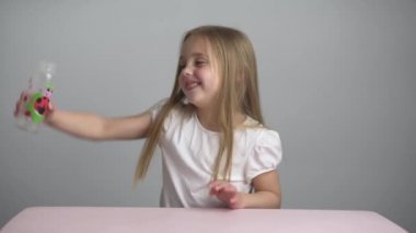 Beyaz tişörtlü, sarı saçlı güzel kız şişeyle oynuyor..