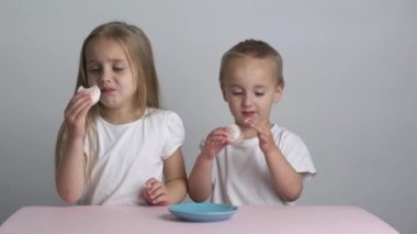 Beyaz tişörtlü, beyaz saçlı, badem kurabiyesi yiyen beyaz erkek ve kız kardeşler.,