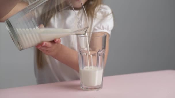 Caucasiano menina close up derrama leite em um copo , — Vídeo de Stock