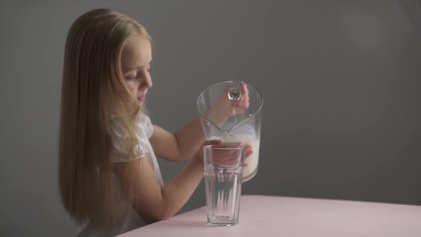 Кавказька дівчинка виливає молоко у склянку. — стокове відео