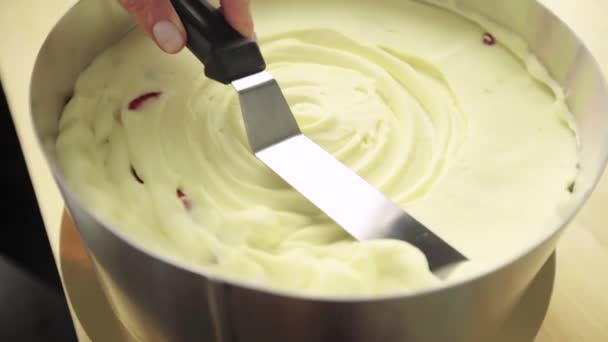 Confectioner udligner fløde på jordbærkage. Kokken skaber en dessert, retter med en spatel og skraber – Stock-video
