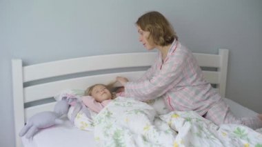 Anne sabah küçük kızını uyandırıyor. Anne ve bebek sabahları yatakta..