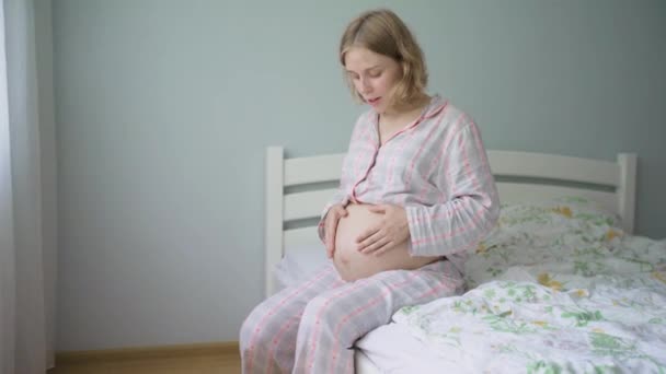 Donna incinta pratica tecnica di respirazione mentre seduto sul letto a casa. — Video Stock