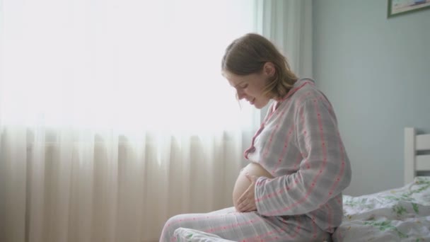 Mulher grávida sentada na cama. Mulher na Dor, Tem Contratos. grávida chama hospital . — Vídeo de Stock