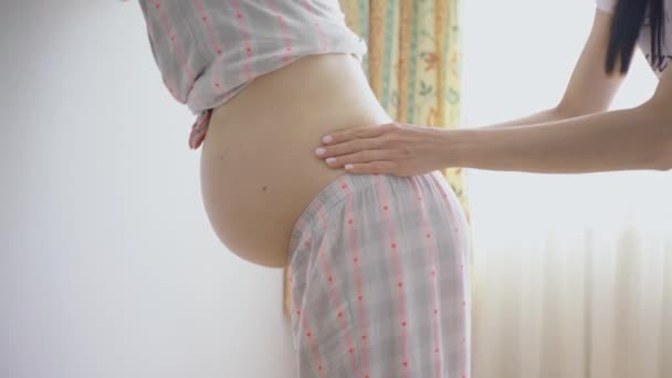 Egy terhes nőt megdörzsölnek és megmasszírozzák a hátát, hogy enyhítse a terhesség fájdalmát.. — Stock videók