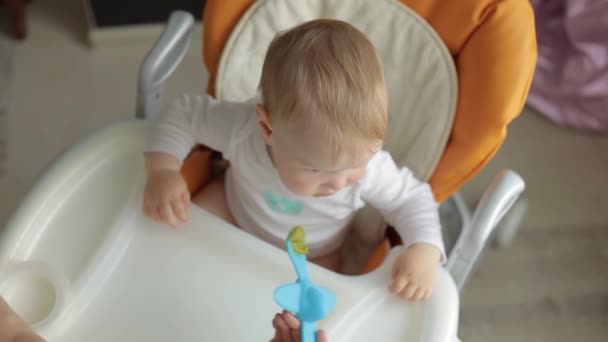 Vista dall'alto. Bambino su una sedia di alimentazione. La mamma nutre il bambino con un cucchiaio. Cucchiaio a forma di aeroplano. — Video Stock