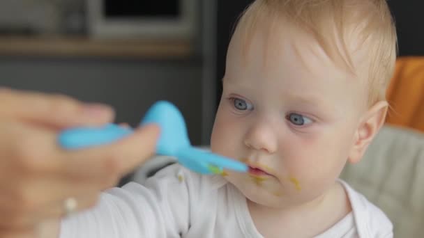 Close-up. Mom feeds the baby with a spoon. Spoon airplane. Baby in a feeding chair. — Stock Video