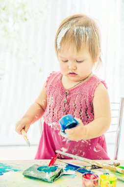 boya tarafından bulaşmış bebek bir yandan bir sanat fırçası tutar, ot