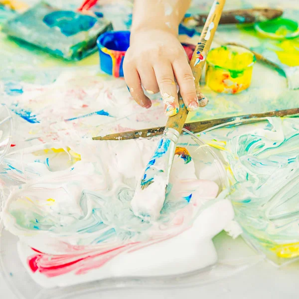 Çocuğun eli bir sanat fırçası tutar ve boya agai içinde dips