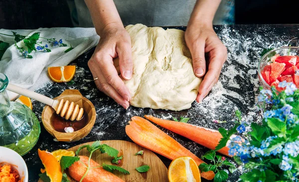 Female hands hold dough against the background of a wooden table Royalty Free Stock Photos