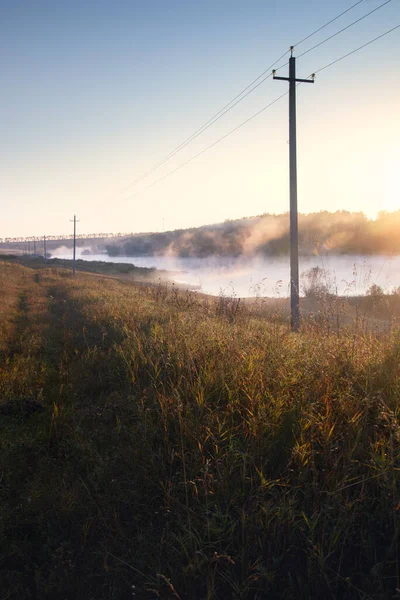 Elektrische Palen Tegen Achtergrond Van Mist Verlicht Door Dageraad Zon Stockfoto