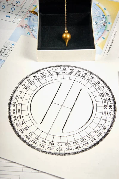 Astrological pendulum for tarot and astrological circle on the background of astrological charts and horoscopes