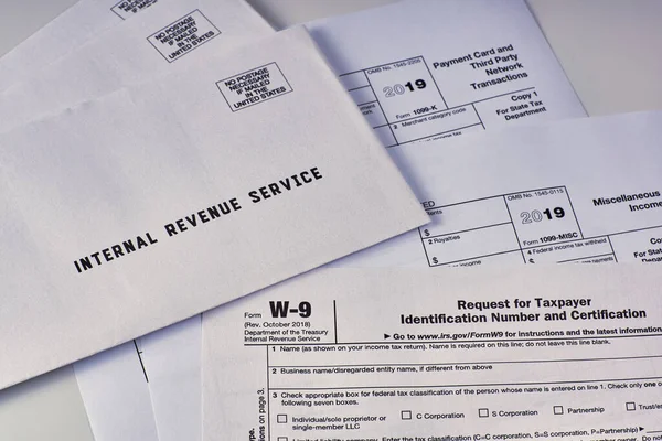 Three mails from the Internal Revenue Service lie on tax Form w-9, 1099-misc, 1099-k on a white background