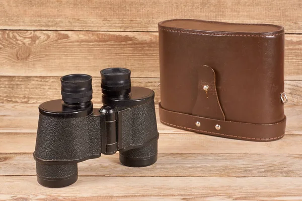 Ancient army binoculars with a case on a wooden background