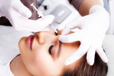 Botulinum toksinin yönetimi sırasında bir kozmetik uzmanı tarafından yakın plan kadın portresi.