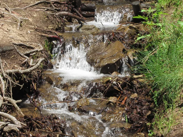 Water stroomt en spatten over rotsen in een bergbeek rivier — Stockfoto