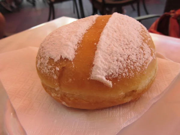 Single Krapfen ( italian doughnut ) covered with icing sugar on napkin — Stock Photo, Image