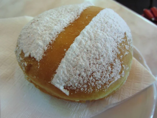 Single Krapfen ( italian doughnut ) covered with icing sugar on napkin — Stock Photo, Image