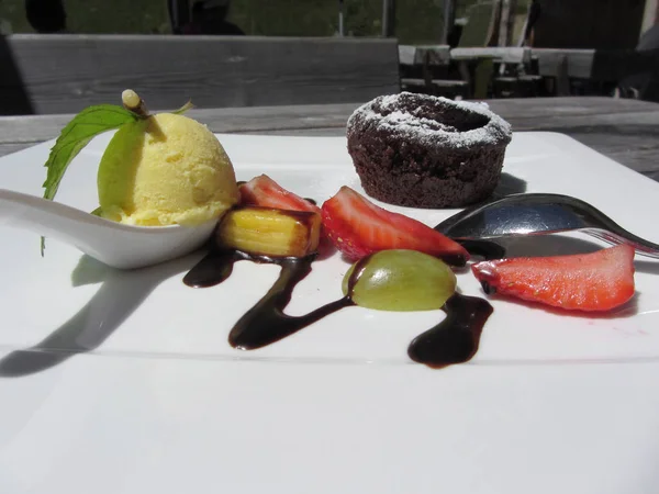 Deliziosa torta al cioccolato fuso con frutta fresca e gelato alla vaniglia sul tavolo in legno rustico all'aperto in estate — Foto Stock