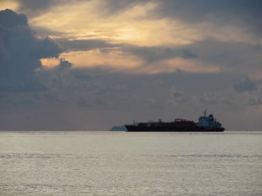 Ufukta kargo gemisi ile sıcak deniz günbatımı . Devler kümülonimbus bulutları gökyüzünde. Toskana, İtalya