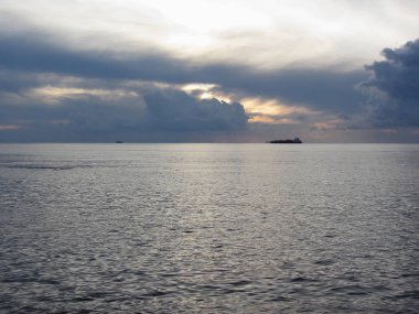 Ufukta kargo gemisi ile sıcak deniz günbatımı . Devler kümülonimbus bulutları gökyüzünde. Toskana, İtalya