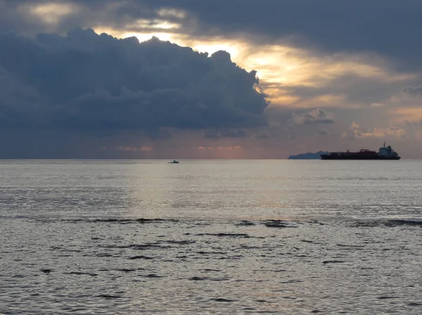 Meleg tengeri naplemente teherhajóval és egy kis halászhajóval a horizonton. Giants Gomolyfelhő magasságban vannak az égen. Toszkána, Olaszország — Stock Fotó