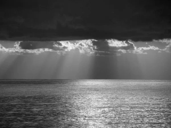 Atardecer cálido mar con gigantes cumulonimbus nubes en el cielo y rayos de sol a través. Foto en blanco y negro. Toscana, Italia —  Fotos de Stock