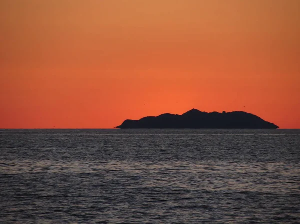 Gyönyörű tengeri naplemente sziget sziluett panoráma. Kilátás Gorgona sziget Livorno város. Toszkána, Olaszország — Stock Fotó