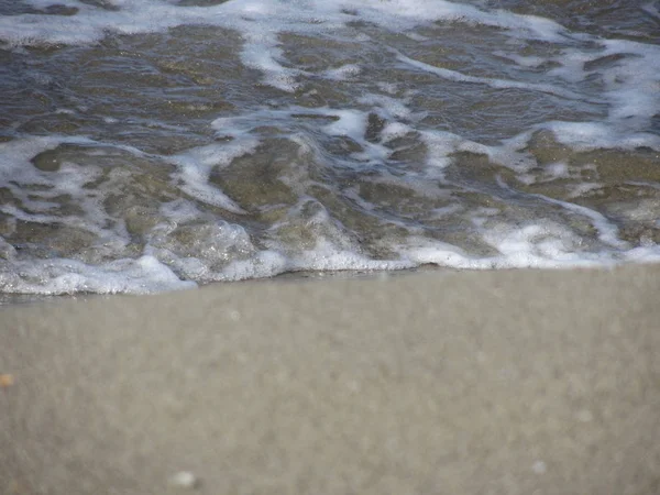 Wave of the sea on the sand beach blurred background — Stock Photo, Image