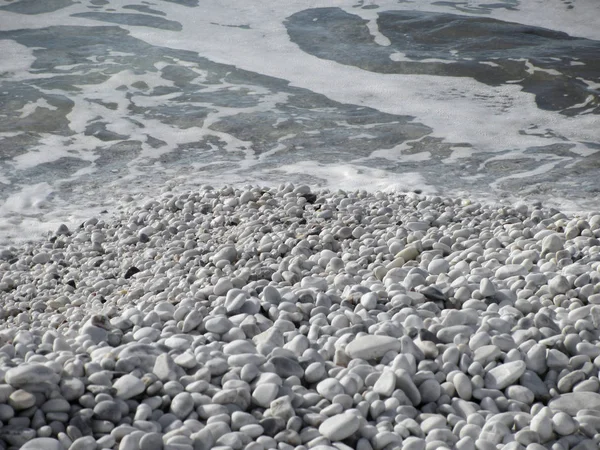 Крупним планом гальковий або кам'янистий або гальковий пляж з гладкими і круглими білими морськими камінцями — стокове фото