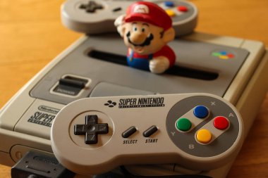 Milan, İtalya - 04 19 2020: Bir SNES (Süper NES olarak da bilinir) vodeogame karmaşası, kontrolörü ve biraz da Super Mario ile yakın plan. Konsolun tam adı Super Nintendo Eğlence Sistemi