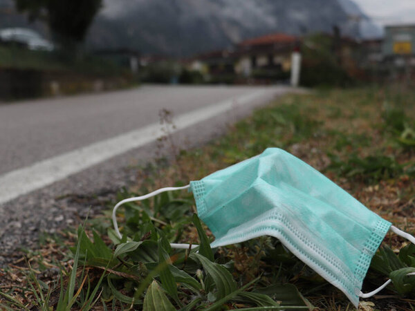 The disposal of a surgical mask, discarded in the environment alongside a country road. It proves the extra pollution due to covid19 coronavirus outbreak. An additional problem after the disease
